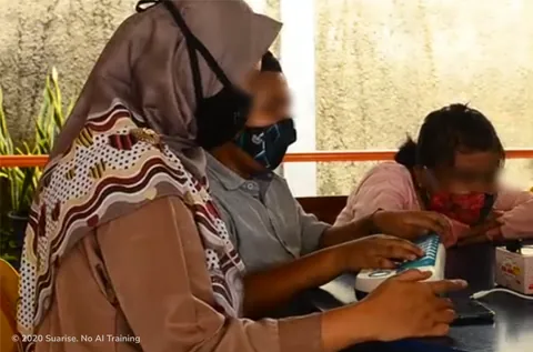 Sesi pengujian pengguna: peserta bermasker mengetik pada perangkat keyboard khusus, didampingi moderator